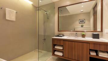 A modern bathroom with a glass shower enclosure, wooden vanity, and a large mirror.