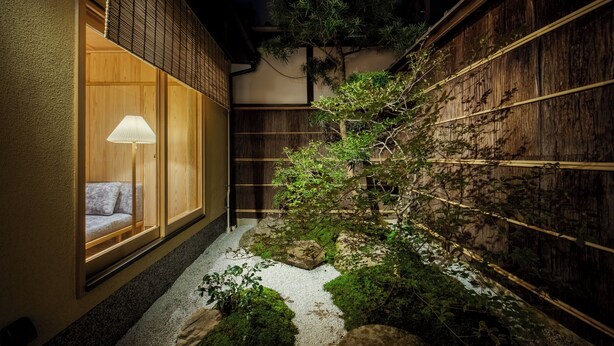 Una habitación tradicional japonesa con suelo de tatami, una mesa de madera baja y una puerta corredera.