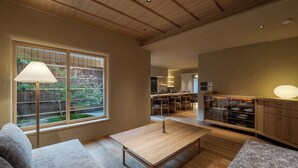 Una sala de estar moderna con una mesa de madera, un sofá y un ventanal con vistas a un jardín.