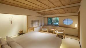 Un dormitorio minimalista con una cama grande, una mesita pequeña y sillas.