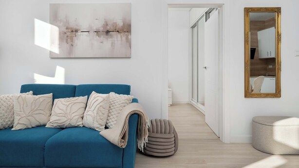 A modern living room with a blue sofa, a beige ottoman, and a large abstract painting on the wall. - Apartment on the Market Square | In the Heart of the Old Town (Wrocław)
