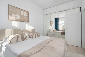 Un dormitorio con cama, armario y espejo.