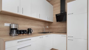 A modern kitchen with white cabinets, a wooden countertop, a coffee maker, and a microwave. - Apartment on the Market Square | In the Heart of the Old Town (Wrocław)