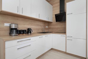 Una cocina moderna con armarios blancos, encimera de madera, cafetera y microondas.