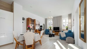 A modern living room with a dining area, a sofa, a TV, and a large mirror. - Apartment on the Market Square | In the Heart of the Old Town (Wrocław)