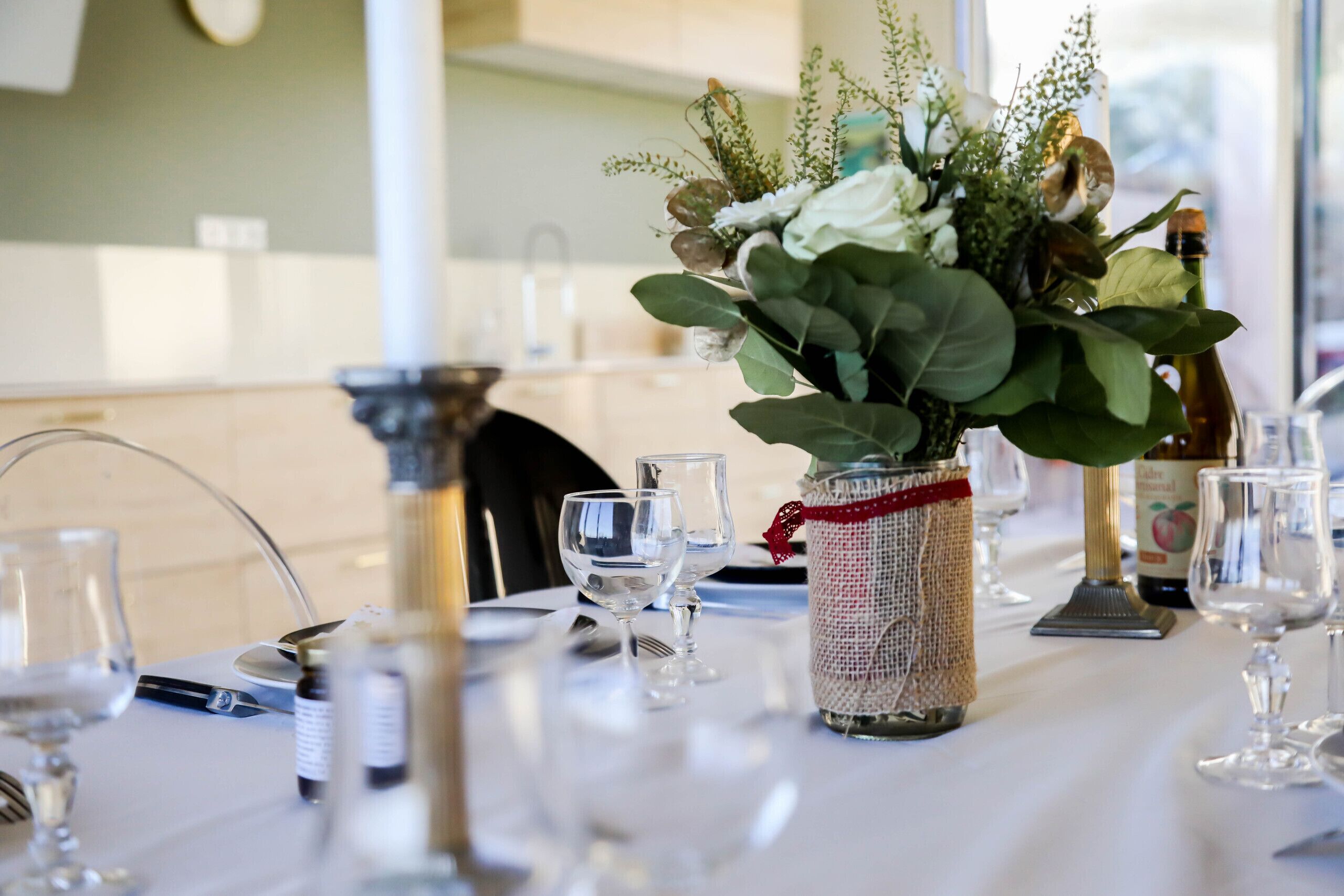 Ein gedeckter Tisch mit einer Blumenvase, Weingläsern und einer Weinflasche.