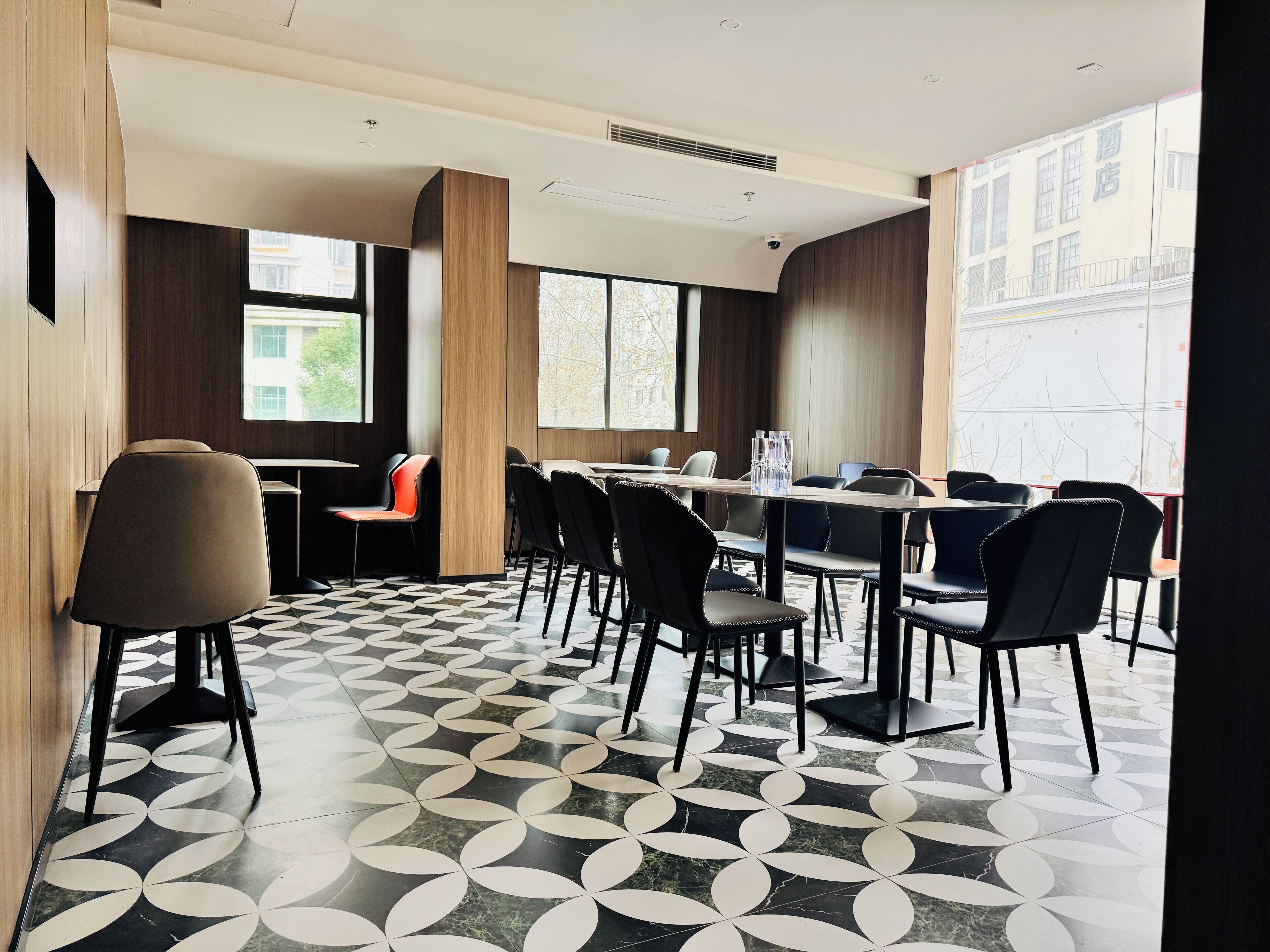 Un salón de conferencias de diseño moderno, con piso estampado, una larga mesa con sillas y amplias ventanas que ofrecen luz natural.
