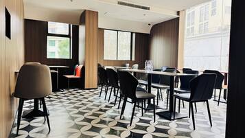 Un salón de conferencias de diseño moderno, con piso estampado, una larga mesa con sillas y amplias ventanas que ofrecen luz natural.