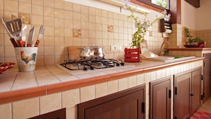 A kitchen with a gas stove, a pot on the counter, and a utensil holder with knives. - Spacious Villa with Garden, WiFI, A/C, Outdoor kitchen, short walk to the Sea (Piana Calzata)