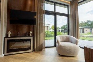 Una sala de estar moderna con chimenea, un sillón cómodo y un ventanal con vistas al exterior.