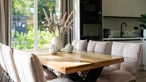 A modern kitchen with a built-in oven and a dining area with a wooden table and cushioned seating. - Residence Winterswijk (Winterswijk - Huppel)