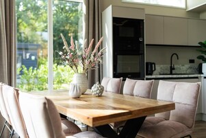 Una cocina moderna con horno empotrado y comedor con mesa de madera y asientos acolchados.
