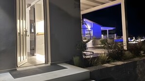 A modern house with a well-lit entrance, a staircase leading to the main door, and a covered outdoor area with plants. - Luxury & Romantic Escape – Ideal for Couples & Newlyweds (Kranidi)