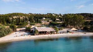 A coastal area with a beach, a building with outdoor seating, and a hilly background. - Luxury & Romantic Escape – Ideal for Couples & Newlyweds (Kranidi)