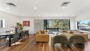 A modern living room with a dining area, large windows, and a balcony.