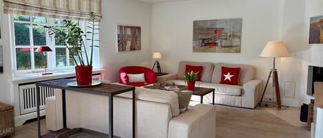 Ein Wohnzimmer mit Sofa, Sessel, Couchtisch und Esstisch.