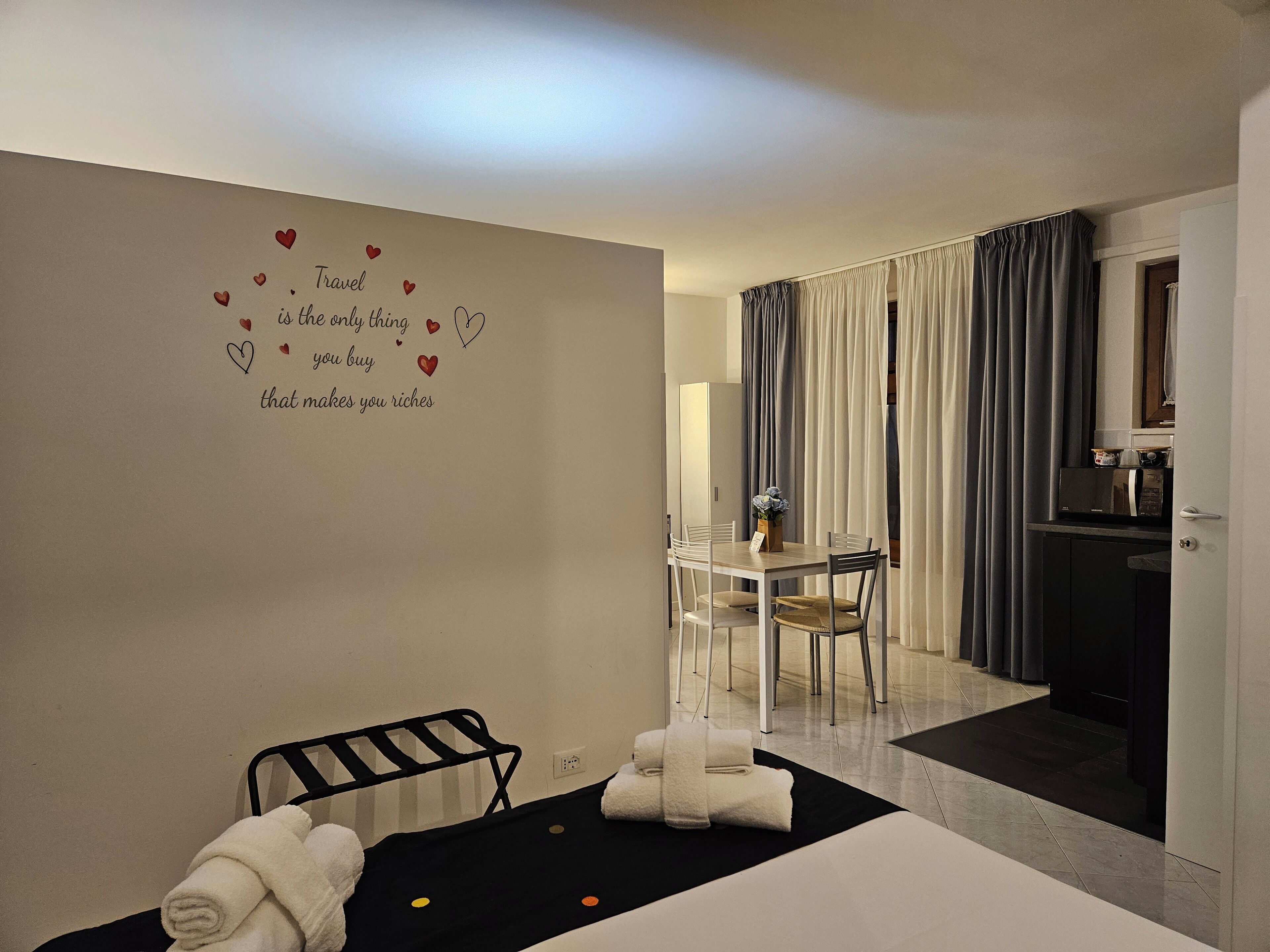 Ein Hotelzimmer mit Bett, einem kleinen Tisch mit Stühlen, einer Küchenzeile und einem Badezimmer mit Dusche.