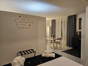Ein Hotelzimmer mit Bett, einem kleinen Tisch mit Stühlen, einer Küchenzeile und einem Badezimmer mit Dusche.
