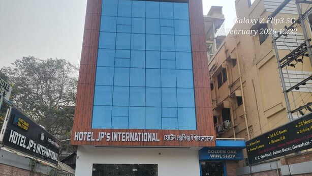Hotel JP's International, con una fachada moderna, una entrada visible y un letrero para la tienda de vinos Golden Oak.