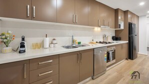 Eine moderne Küche mit braunen Schränken, einer Edelstahl-Spüle und einem schwarzen Kühlschrank.