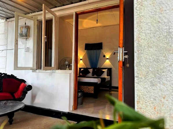 Una habitación con una cama, una ventana, un ventilador y una mesa.