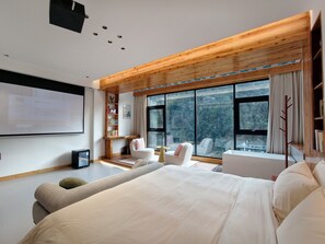 A modern bedroom with a large bed, a desk, and a chair. There is a bookshelf and a window with a view of trees. - Zhangjiajie Zhiguiju (Zhangjiajie)