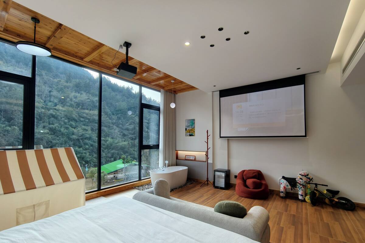 Un dormitorio moderno con una cama grande, un escritorio y una pantalla de proyector.