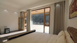 A bedroom with a large bed, a desk, and a view of a balcony. - Zhangjiajie Zhiguiju (Zhangjiajie)