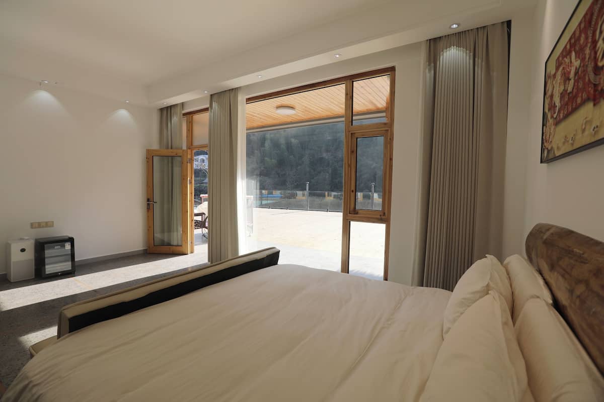 Un dormitorio con una cama grande, un escritorio y vistas a un balcón.