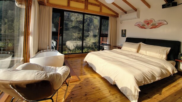 Quarto com uma cama grande, uma cadeira, uma janela e vista para o exterior.