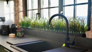 Una cocina con un grifo moderno, un lavamanos y un ventanal con vistas a zonas verdes.