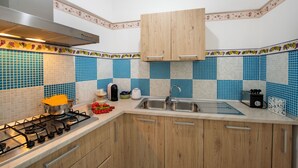 Eine Küche mit Gasherd, Spüle, Holzschränken und einer blau-weißen Küchenrückwand.