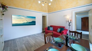 Ein Essbereich mit einem Holztisch, gedeckt für vier Personen, einem roten Sofa und einem großen Landschaftsbild an der Wand.
