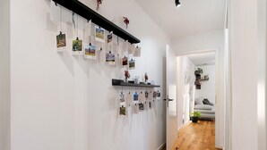 Un passadís amb sòl de fusta, parets blanques i una estant negra amb fotos i notes.