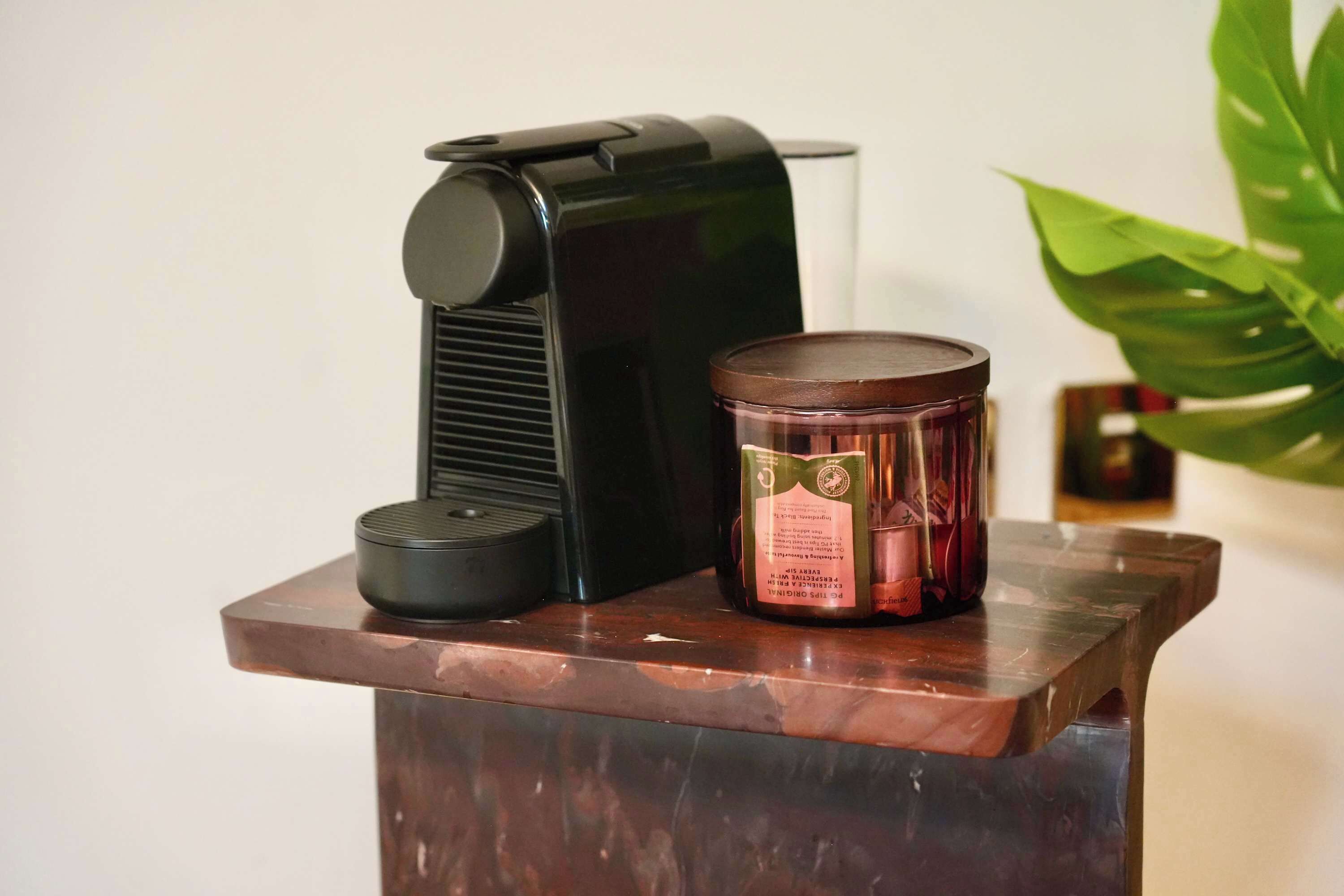 A coffee maker and a candle on a wooden table.