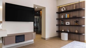 A modern living room with a flat-screen TV mounted on the wall, a built-in fireplace, and a wooden bookshelf with various decorative items. - Maison Privee - Ultimate Luxury Penthouse w/ Pool & Marina Views (Dubai)