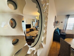 A modern living room with a unique wall design, a dining area with a round table, and a sofa with cushions. - The pearl of Le Crotoy sea view (Le Crotoy)