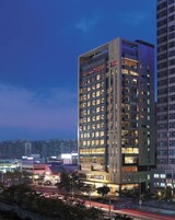 A multi-story hotel with a modern design, featuring a prominent entrance and multiple floors with illuminated windows.
