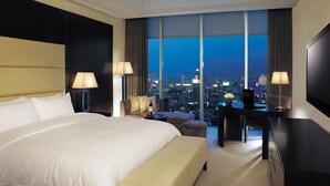Una habitación de hotel con una cama grande, un escritorio y vistas a la ciudad de noche.