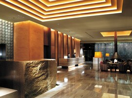 A modern lobby with a reception desk, seating area, and a patterned wall.