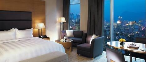 Habitación de hotel con cama, escritorio, silla, sofá y vista a la ciudad.