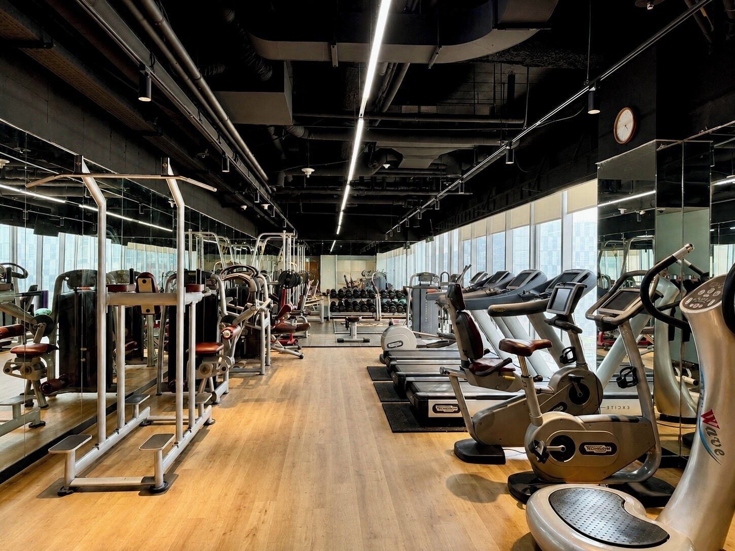A gym with cardio machines, weightlifting equipment, and mirrors on the walls.