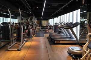 Un gimnasio con cintas de correr, máquinas de pesas y un espejo grande.