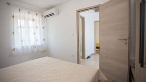 Una camera da letto con un letto, condizionatore d'aria, una porta e vista su un'altra stanza.