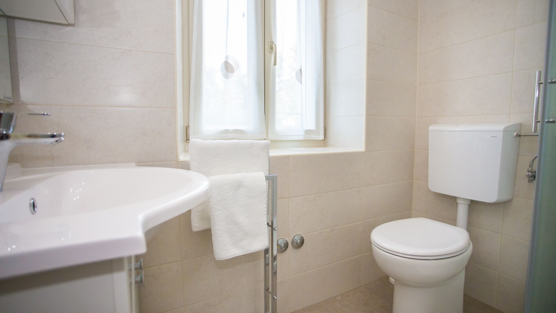 Ein Badezimmer mit Waschbecken, Toilette und Fenster mit Vorhängen.