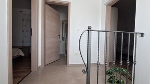 Un corridoio con una porta in legno, una ringhiera in metallo e una pianta.