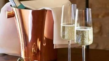 A copper champagne bucket with a bottle and two glasses on a wooden table.