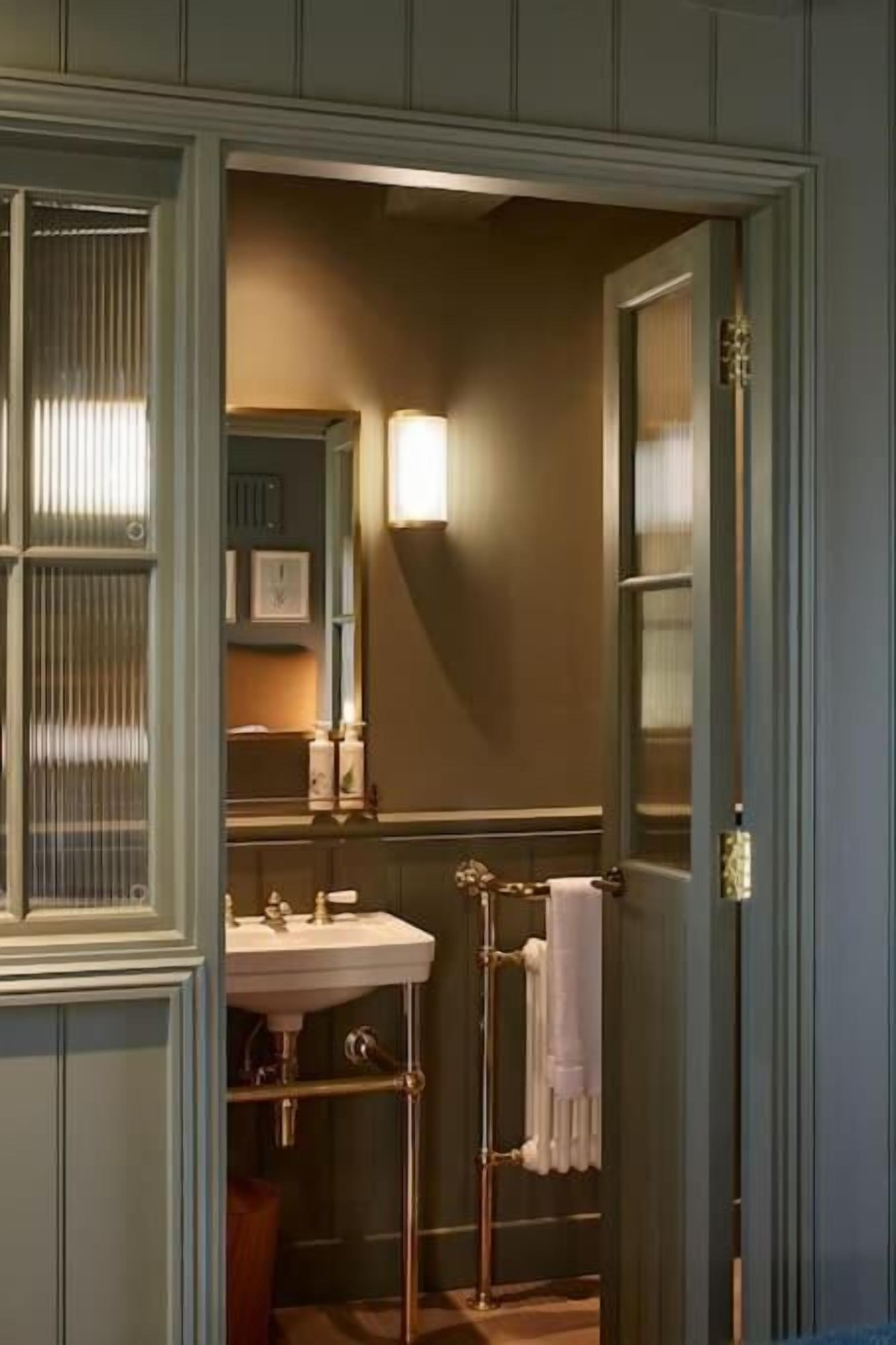 Une salle de bain avec un lavabo blanc, un porte-serviettes et un miroir.