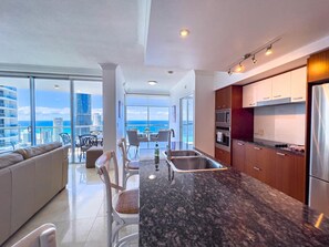 A modern kitchen with a large island, stainless steel appliances, and a view of the city skyline. - Surfers Paradise 32nd-Floor Ocean View Apartment (Surfers Paradise)