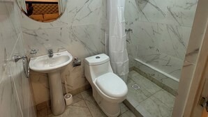 Une salle de bain avec des toilettes, un lavabo et une douche.